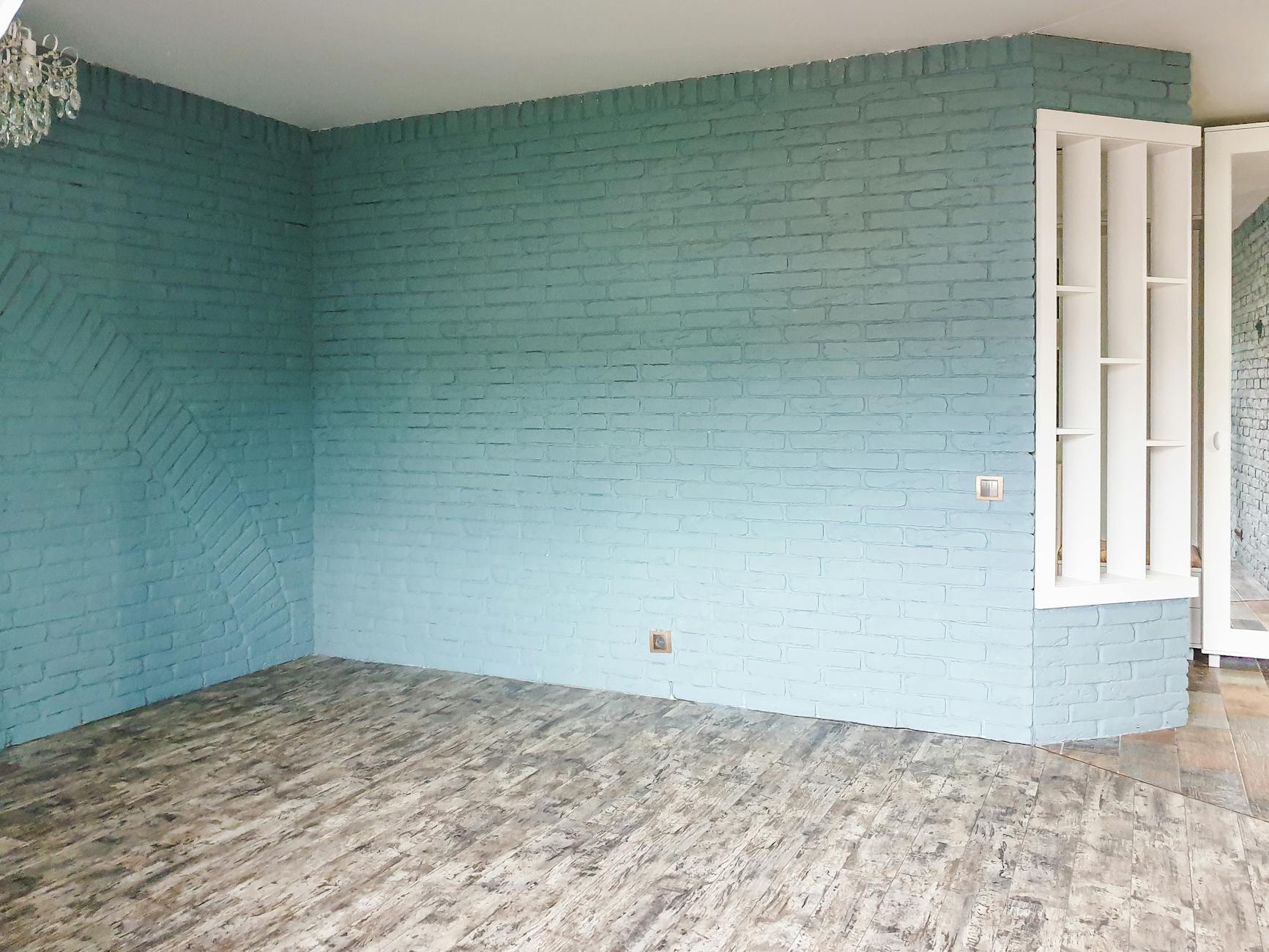 Puste wnętrze z niebieską ceglaną ścianą i drewnianą podłogą