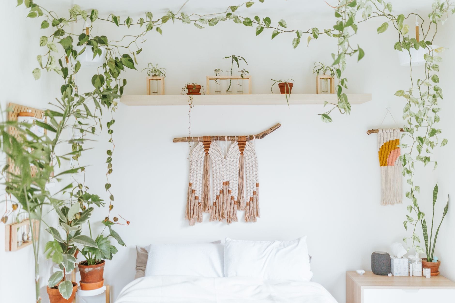 Jasna sypialnia boho z wiszącymi roślinami i minimalistycznymi dodatkami